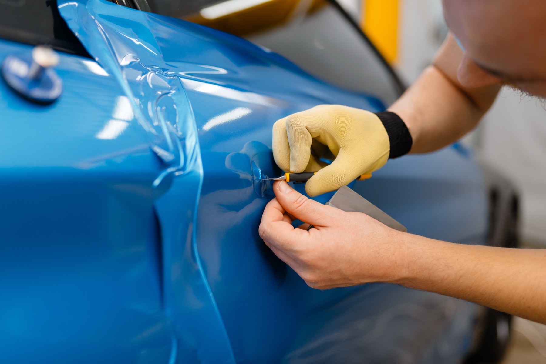 An installer smoothing blue film onto a car