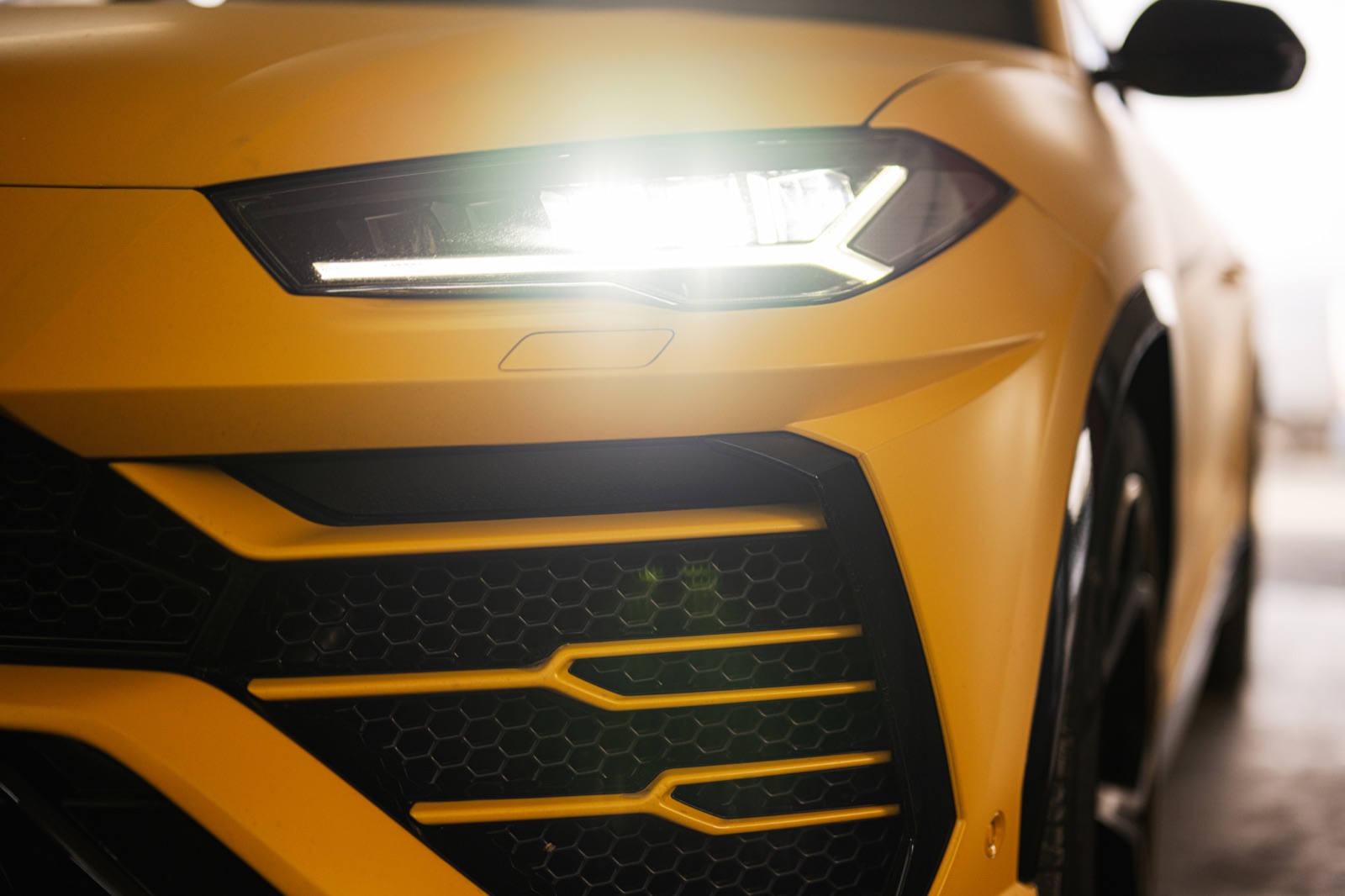 The front of a yellow SUV with its headlights on